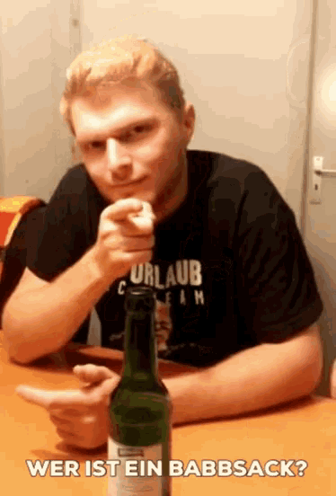 a man sitting at a table with a bottle of beer and the words wer ist ein babbsack