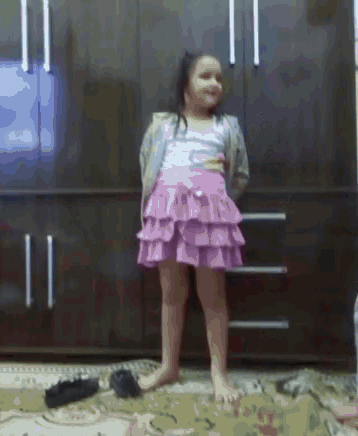 a little girl in a pink skirt is standing on a rug .
