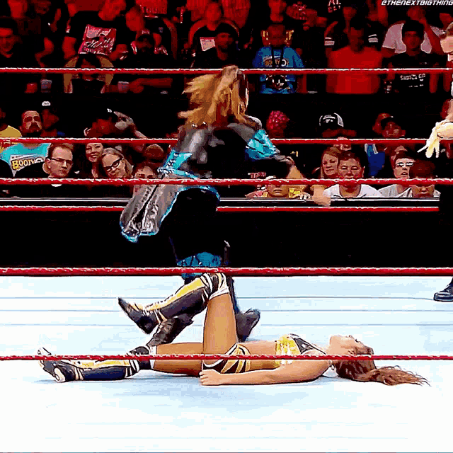 a woman in a wrestling ring with the next thing written on her shirt
