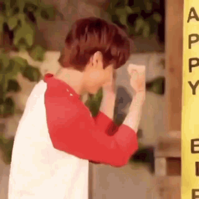 a man in a red and white shirt is standing in front of a yellow sign and making a funny face .