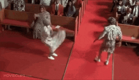 two women are dancing on a red carpet in front of a crowd of people in a church .