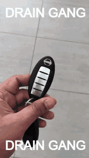 a person holding a nissan key with the words drain gang written on it