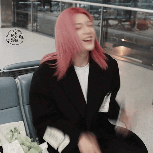 a woman with pink hair sits in a chair with chinese writing on it