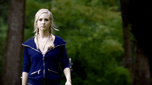 a blurry picture of a woman in a blue jacket standing in the woods .