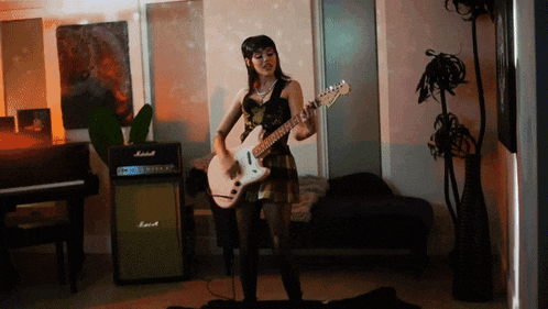 a woman is playing a guitar in front of a marshall amp