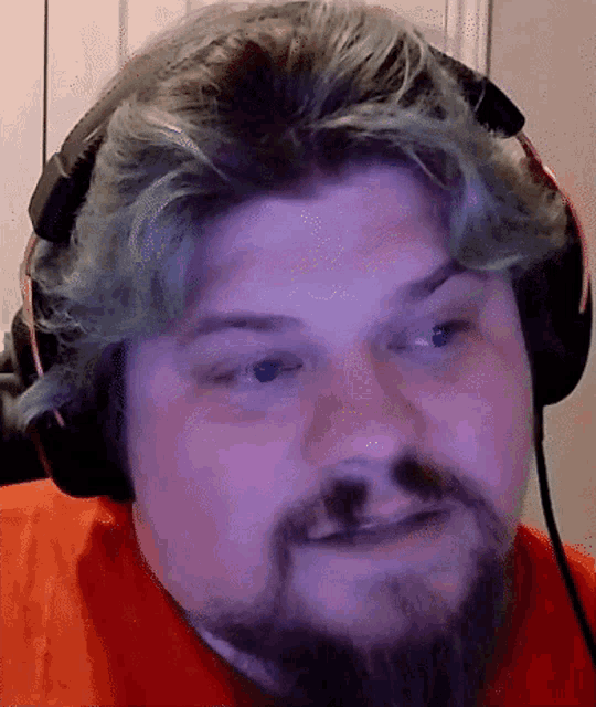 a man with blue hair and a beard wearing headphones and a red shirt