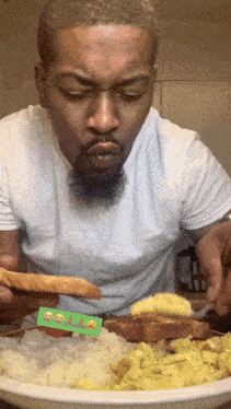 a man in a white shirt is eating a plate of food with smiley faces on the spoon