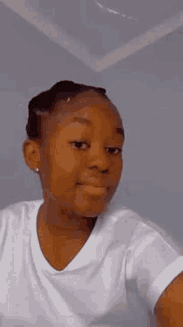 a young girl in a white t-shirt is taking a selfie with her phone .