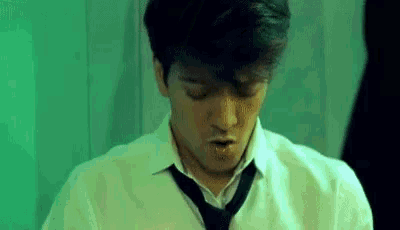 a man in a white shirt and tie is looking down at something .