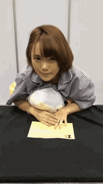 a young woman is sitting at a table with a stuffed animal on her lap .