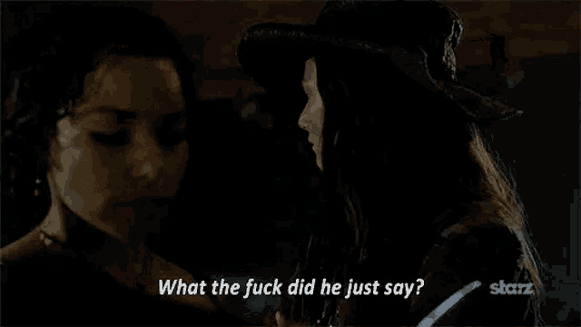 two women are standing next to each other in a dark room and one of them is asking the other what the fuck did he just say .