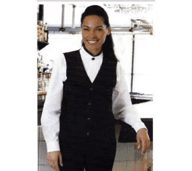 a woman wearing a black vest and a white shirt is standing in a bar .