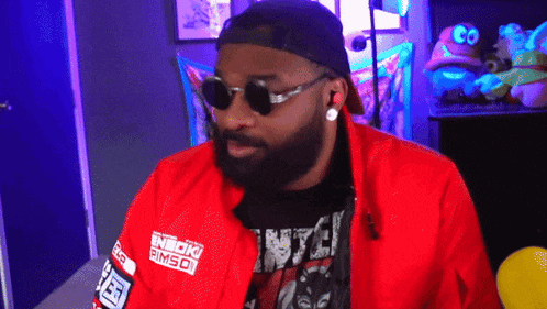 a man with a beard wearing sunglasses and a red jacket that says emporio armani