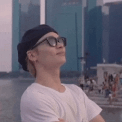 a man wearing sunglasses and a beret is standing in front of a city skyline .