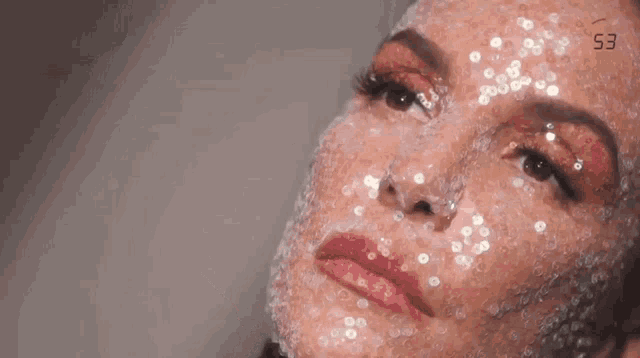 a close up of a woman 's face covered in sequins .