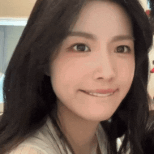 a close up of a woman 's face with long black hair smiling .