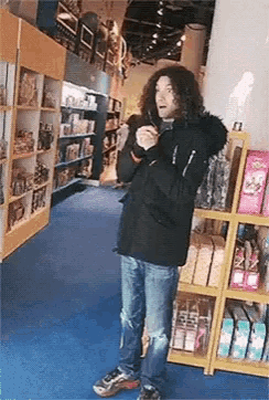 a man with long curly hair is standing in a store holding a bottle