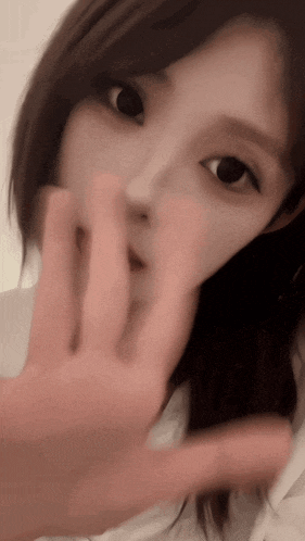 a close up of a woman 's face with a hand covering her mouth