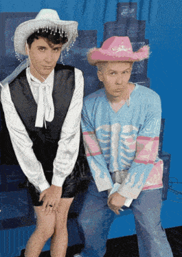 a man wearing a pink cowboy hat is standing next to another man wearing a skeleton shirt