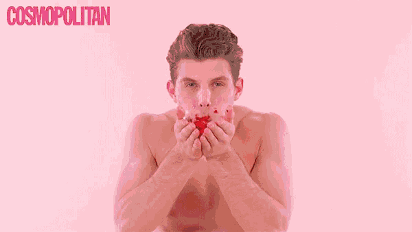 a shirtless man is blowing confetti in front of a pink background that says cosmopolitan