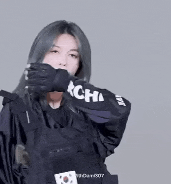 a woman wearing a black jacket and gloves is holding a gun .