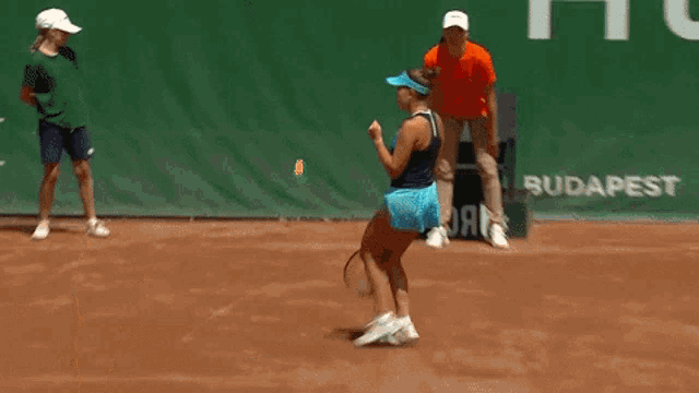 a woman wearing a blue visor and a blue tank top stands on a tennis court