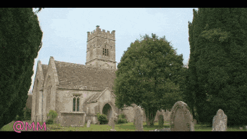 a cemetery with a church in the background and the letters mm on the bottom right