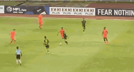 a group of soccer players are playing on a field with a sign that says fear nothing on it