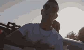 a man wearing sunglasses is standing in front of a car .