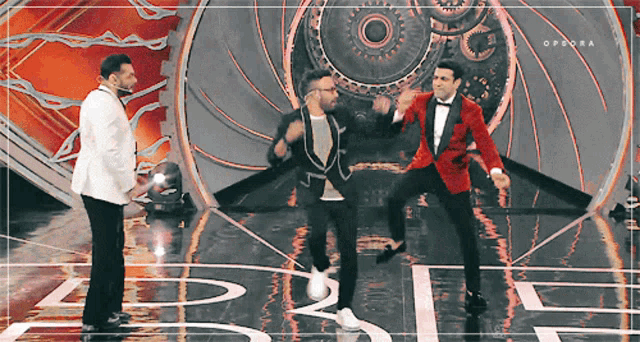 three men in tuxedos are dancing on a stage and the word opdora is on the bottom