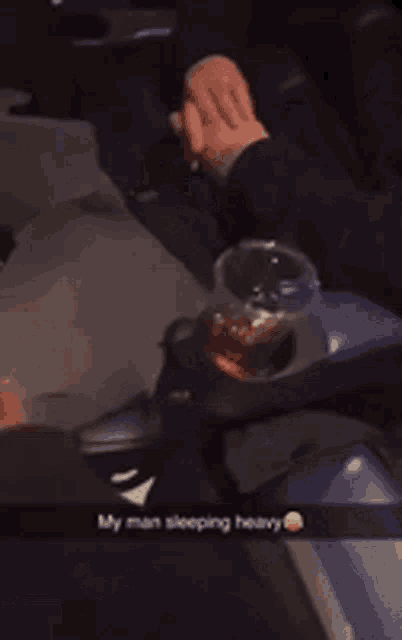 a man sits in a chair with a drink in his hand and a caption that says my man sleeping heavy