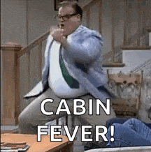 a man in a suit and tie is dancing in a living room with the words `` cabin fever '' .