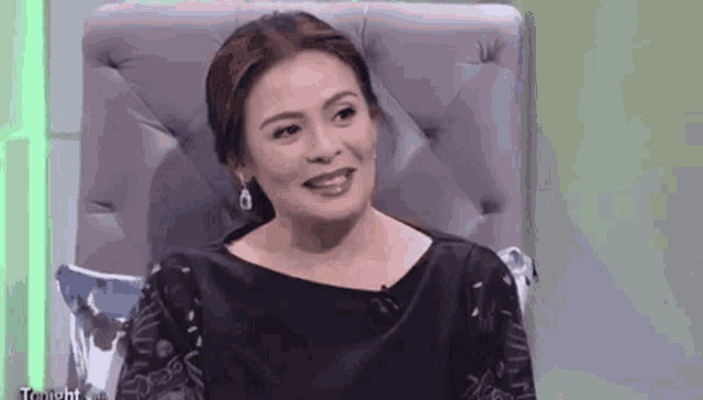 a woman is sitting in a chair with a microphone in her hand and smiling .
