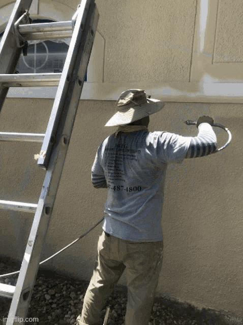 a man wearing a shirt that says mcg on the back is spraying paint on a wall