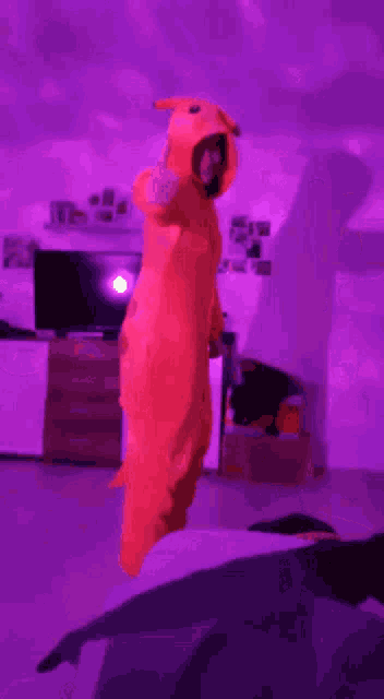 a person in an orange costume is standing in front of a purple light .