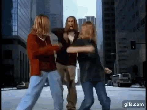 a group of people are dancing on a city street with a gif.com icon in the corner