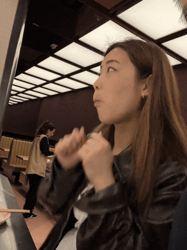 a woman sitting at a table in a restaurant with chopsticks