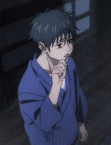 a boy in a blue kimono is standing in a dark room .