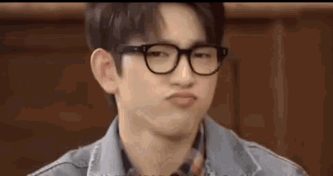 a close up of a young man wearing glasses making a funny face .