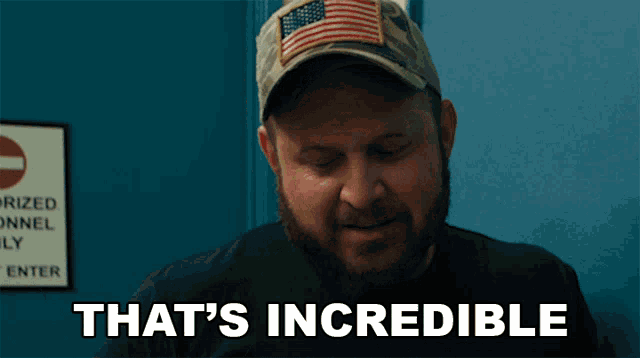a man in a hat says that 's incredible in front of a blue wall