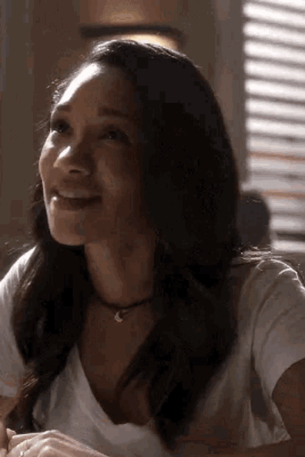 a woman is sitting at a table smiling and looking up at the sky .