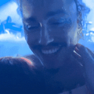 a man with a tattoo on his face is smiling in a blurry photo