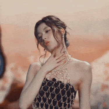 a woman wearing a black and gold dress with pearls