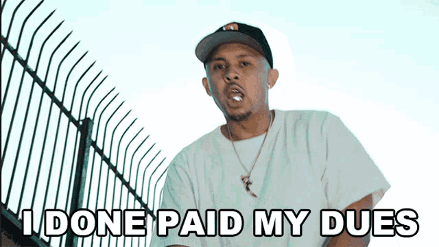 a man in a hat says " i done paid my dues " in front of a fence