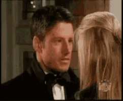 a man in a tuxedo is standing next to a woman in a black jacket .