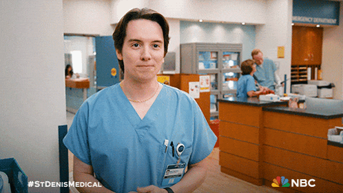 a nurse in a blue scrub stands in front of an emergency center