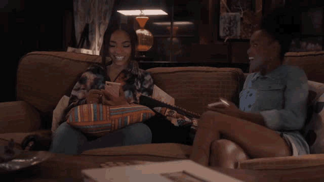 two women are sitting on a couch talking