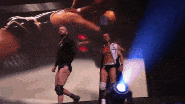 two wrestlers are walking in front of a large screen that says aa on it