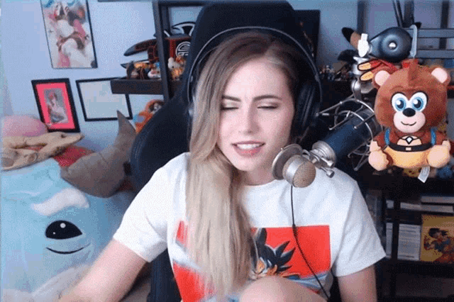 a woman wearing headphones is sitting in front of a microphone and a stuffed bear