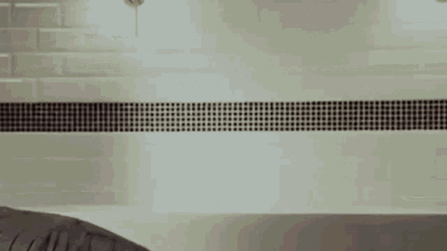 a man is taking a shower in a bathroom with his head sticking out of the bathtub .